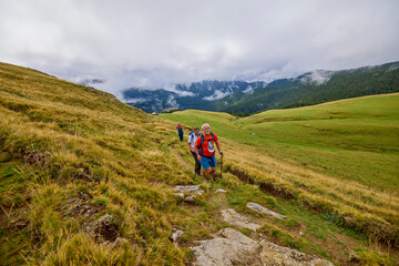 Fototapeta premium a couple with their grandfather walking in the mountains on a cloudy and foggy day.