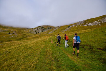 Fototapeta premium a couple with their grandfather walking in the mountains on a cloudy and foggy day.