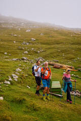 Fototapeta premium a couple with their grandfather walking in the mountains on a cloudy and foggy day.