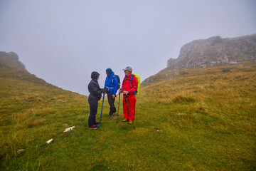 Obraz premium a couple with their grandfather walking in the mountains on a cloudy and foggy day.