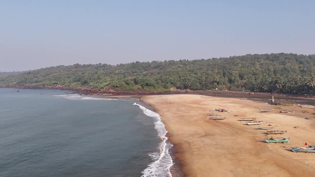 Aerial view of a traditional fishing village on Kelus Kalvi Beach, with colorful boats resting on the sand along the Konkan coast in India.