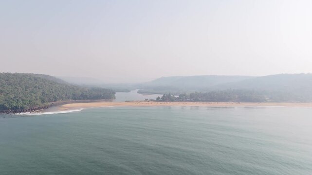Expansive aerial view of Kelus Kalvi Beach in Maharashtra, India, where a river meets the Arabian Sea, creating a beautiful sandy estuary.