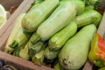 Fresh vegetables sold at an open market stall. Zucchini stacked in a pyramid, close-up of the counter in the store