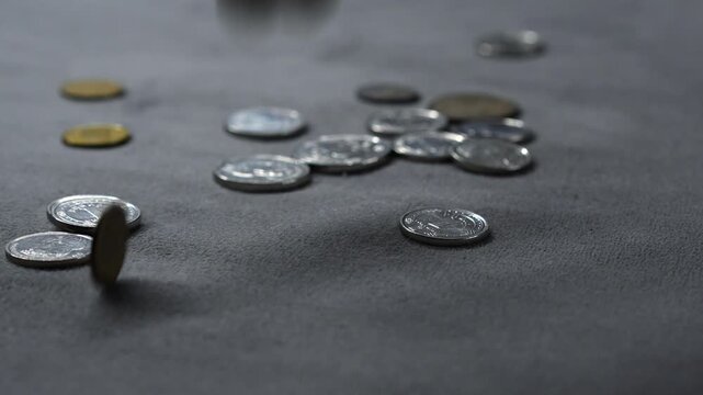 Metal coins fall onto a gray surface and spill in all directions,
Coins raining down from above onto the surface.
Many kopecks fall onto the gray table.
Money, coins, kopecks, pennies