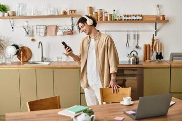 Stylish young man enjoying music while relaxing in a modern kitchen at home