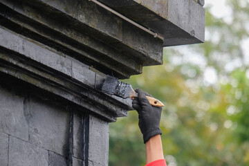 Close up of hands painting a building black using a brush. For graphic design, 3D rendering and banner backgrounds