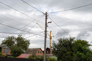Obraz premium Concrete electric pole with wires against gray sky 