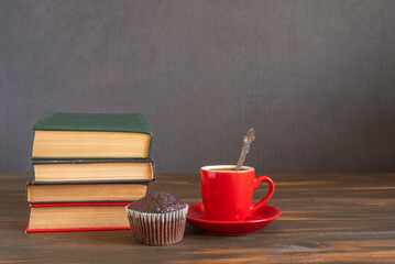 Old books and cup of coffee on dark wooden background with copy space. Library concept.
