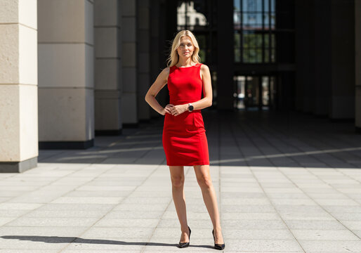 Young woman standing confidently in a red dress outdoors  