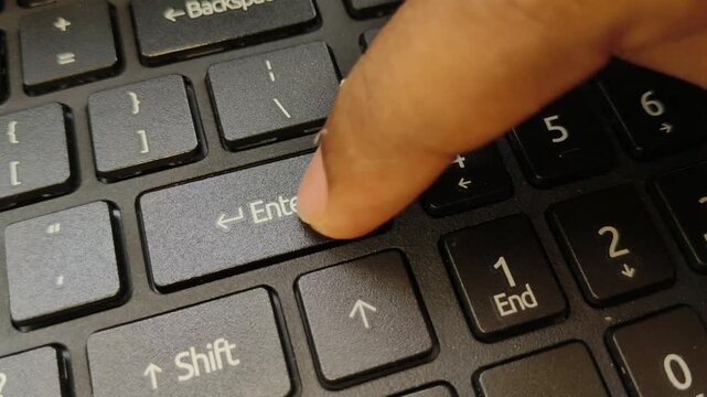 Close up macro top view of finger pressing or rage clicking laptop enter button on keyboard. Frustration or angry on unresponsive or frozen computer concept.