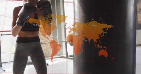 Striking athlete practicing boxing with gloves and bag in studio, digital world map overlay