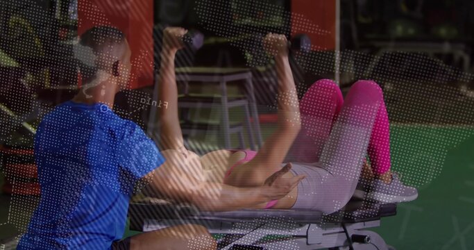 Fototapeta Lying on flat bench performing dumbbell chest press in gym strength area, trainer spotting