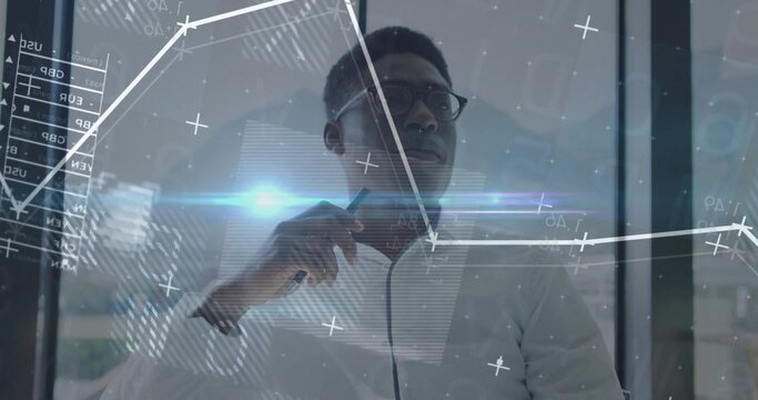 Analyzing digital charts on glass board in office, businessman in white shirt, glasses with marker