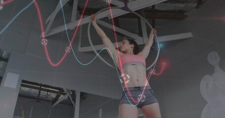 Suspending athlete wearing sports bra, shorts on aerial hoop in gym, with rigging, waveform overlay