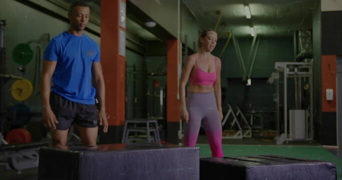 Standing workout partners performing plyometric box jump warmup at gym, with weight plates