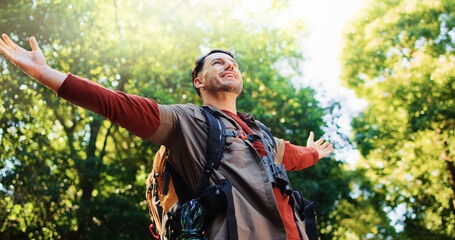 Happy man, freedom and hiking in forest with achievement, goals and stretching arms in nature. Person, smile and excited in woods with success for trekking adventure with low angle in Australia