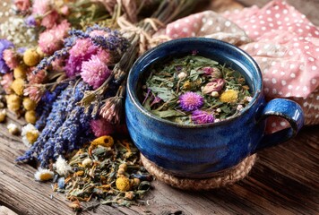 Steaming herbal tea in a dark blue mug, presented with dried flowers and a rustic wooden background