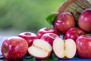 Red Applw on green nature bokeh background. Many Red apples in basket on wooden table.