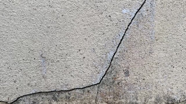 Dirty cracked concrete wall close-up video showing surface damage and weathered detail.
