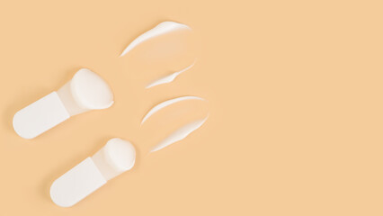 Natural beauty concept: cosmetic spatulas with cream texture on beige background.