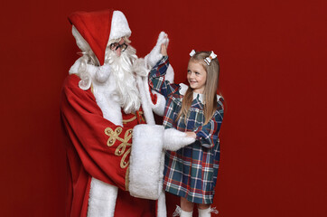 Santa Claus and little girl high five on red background