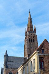 Obraz premium Explore the stunning Church of Our Lady in Brugge, Belgium. This image captures the church s impressive tower and unique architecture against a bright blue sky. A must-see in Brugge, Belgium.