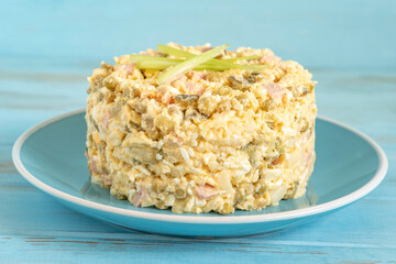 Russian potato salad Olivier on blue ceramic plate.