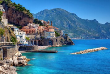Naklejka premium Picturesque coastal town clings to rocky cliffs, with colorful buildings overlooking clear blue water and distant mountains under a sunny sky