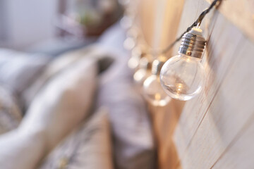 Cozy bedroom decor with string lights hanging on wooden headboard creating soft ambient glow.