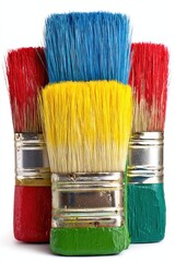 Trio of paintbrushes, brightly colored in red, blue, yellow, and green, stand upright against a white background, bristles angled slightly