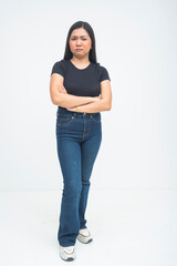 An upset young Asian woman captured in a full body shot with arms crossed tightly, a furrowed brow, and a displeased look while standing. Isolated on a white background.
