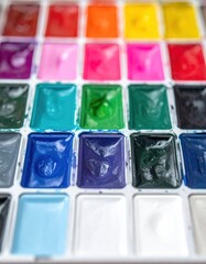 An artist's watercolor paint box with square compartments filled with diverse, vibrant hues, creating a colorful and artistic display