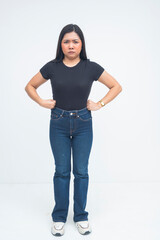 A displeased young Asian woman standing with her hands on her waist, furrowing her eyebrows in anger and showing disagreement. Isolated on a white background.