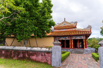 An ornate, traditional Vietnamese pavilion with a distinctive orange tiled roof and vibrant red...