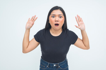 An astonished young Asian woman in a half body shot raising her hands with mouth open and wide eyes, expressing a wow and unbelievable reaction. Isolated on a white background.