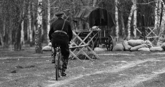 Historical Re-enactment Black And White Video. Re-enactor Dressed As Nkvd Forces Rides A Bike. Peoples Commissariat For Internal Affairs, Abbreviated Nkvd, Was The Interior Ministry Of The Soviet
