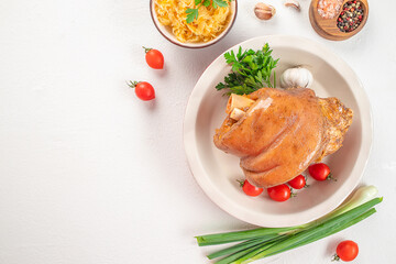 Roasted pork knuckle with vegetables on white background