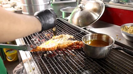 Street Vendor Basting Grilled Lobster in Bangkok Night Market