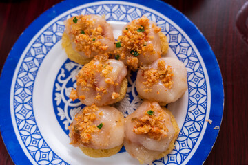 Six servings of  Ram It Cake  from Hue are presented on a blue and white patterned plate, featuring steamed rice cakes on fried crispy bases.
