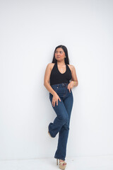 A graceful young Asian woman in a half body shot leaning on a wall, one foot resting on it while looking sideways with poise and sophistication. Isolated on a white background.