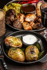 Grilled meat and baked potatoes with sauce.