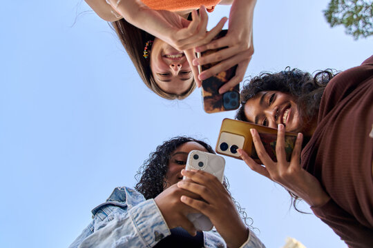 Three young women using smartphones against blue sky