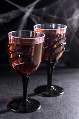 Halloween spooky red cocktail in skeleton hand glass on black background