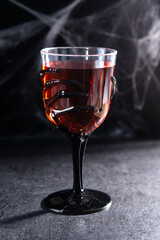 Halloween spooky red cocktail in skeleton hand glass on black background