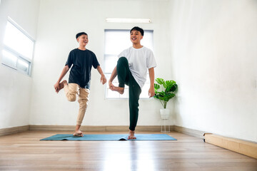 Fototapeta premium Two Joyful Teenage Boys Practicing Yoga Poses Standing With Holding Legs Together