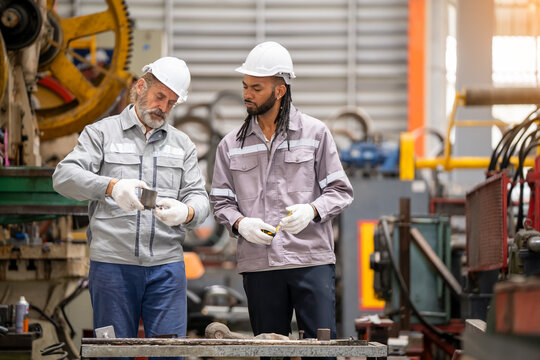 Mentorship in manufacturing skilled workers collaborate in industrial workshop environment