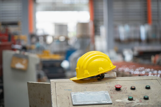 Safety gear in industrial setting yellow hard hat on control panel factory interior focused view workplace safety concept - Powered by Adobe