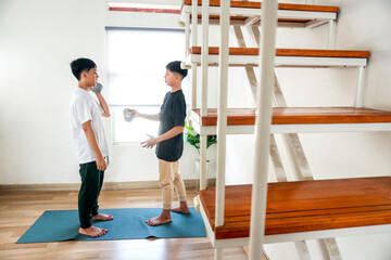 Portrait Of Two Young Brothers Playfully Lifting Dumbbells Together