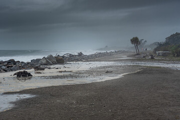 Stormy Weather Rolling Onto Rocky Shoreline with Palm Trees and Wild Driftwood at Hokitika Beach, West Coast, New Zealand