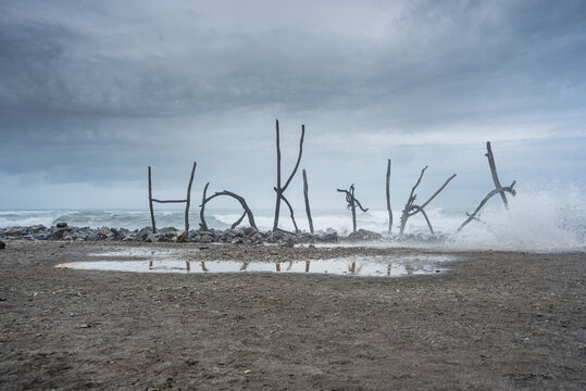 Driftwood Sculpture Spelling &acirc;&euro;Hokitika&acirc;&euro;&trade; on Misty Beach with Reflections on Wet Sand, West Coast, New Zealand